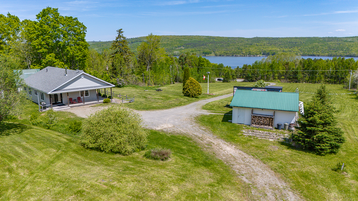 View of home, garage, and river | 6800 Route 102, Dumfries, NB E6G 1N9 | Home For Sale with Barn Near Fredericton